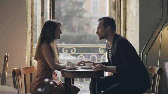 一对情侣在一个舒适的咖啡馆里接吻一个男人和一个女人在餐桌上温柔的接吻