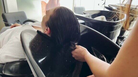一个理发师洗一个女人的头发的细节解开它的剪