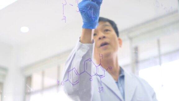 男化学家自信地在透明的板上绘制配方