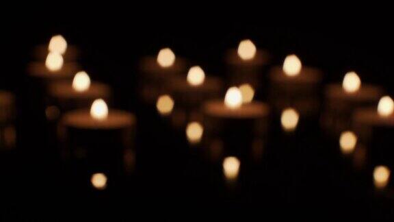在透明的表面上燃烧的蜡烛在黑暗中失去焦点