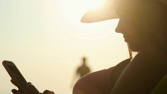 美丽的少女在海滩上使用智能手机的特写