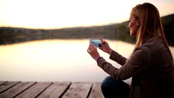 在日落时用手机拍照的女人