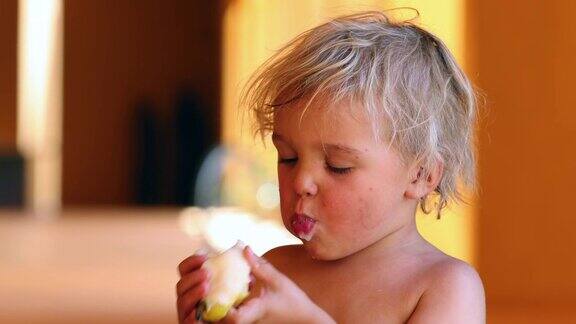 小男孩在阳光下吃梨子4k剪辑分辨率的婴儿金发男孩吃健康的水果