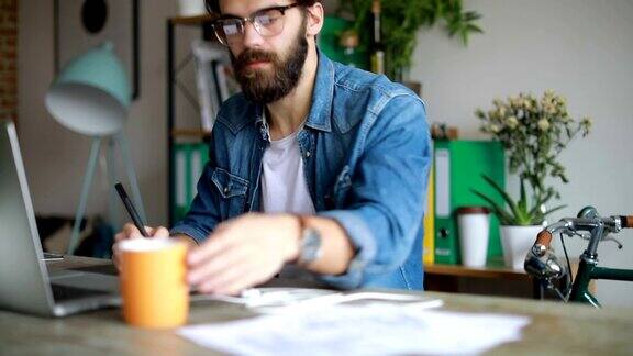 胡子设计师喝着咖啡在数字板上工作