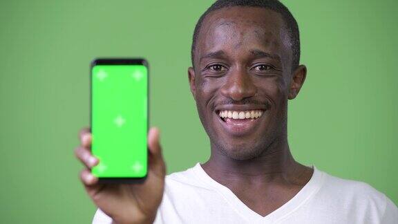 年轻快乐的非洲男子微笑着向镜头展示手机
