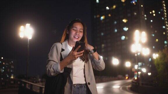 女性晚上在城市使用智能手机