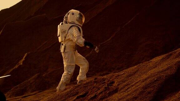 宇航员登上高山探索红色星球火星背景:他的基地和人工智能驱动的漫游车未来殖民