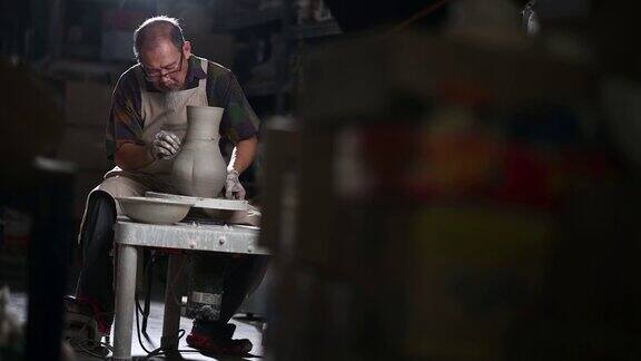 亚洲华人高级泥塑艺术家工作在他的工作室与纺织陶轮