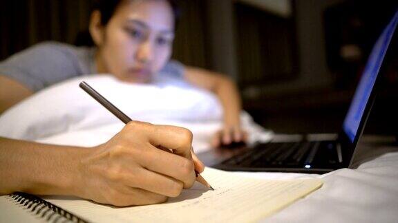 亚洲女性使用笔记本电脑并在笔记本上写字