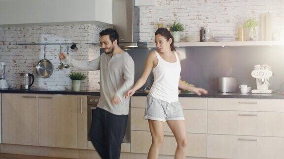 快乐的夫妇在厨房里创造性地跳舞他们都很可爱微笑着