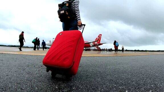 带着红色行李走向飞机的女性旅客