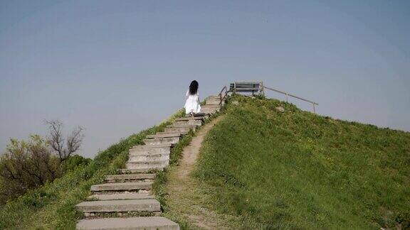 优雅的女人在绿山上爬楼梯