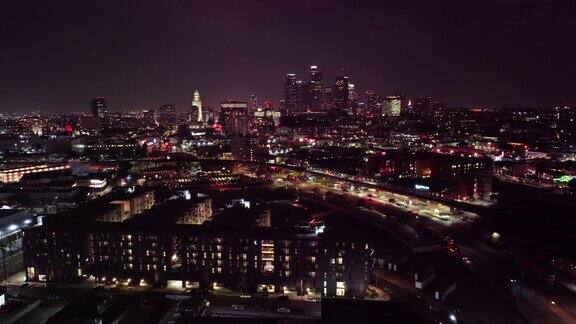无人机在夜间飞过洛杉矶唐人街远处有灯光照亮的市中心
