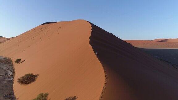 空中放大的男性游客在纳米布沙漠的沙丘上行走