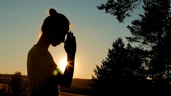 日落时在森林里祈祷的运动女人