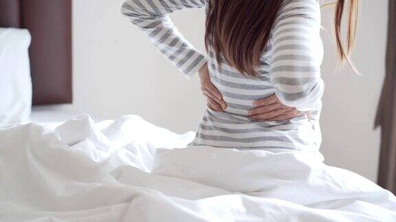 妇女遭受背痛在床上早上保健和问题