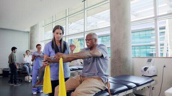 在物理治疗过程中老年男子在物理治疗师的帮助下使用阻力带