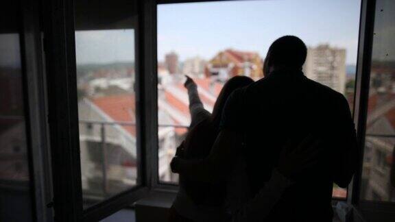 一对年轻夫妇在他们新家的阳台上做着白日梦