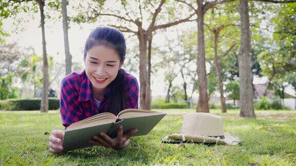 一个年轻的亚洲女人躺在公园里看书