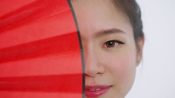 中国亚洲美女春节脸部特写红色扇子遮住了她的右半边脸看着镜头