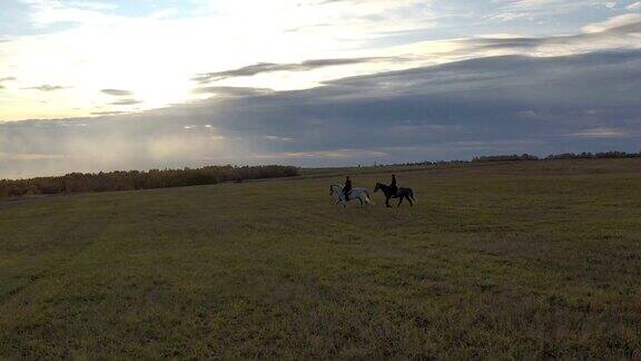 夕阳西下时两个女骑手骑着马穿过田野