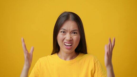不满的韩国年轻女士在黄色背景下皱眉摇头