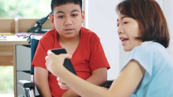 女性看护者帮助残疾男孩(10-11岁)在家通过智能手机接受教育