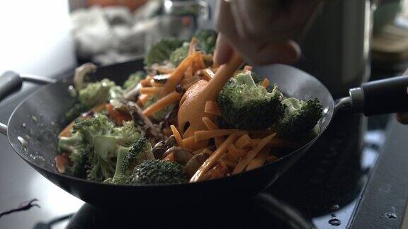 厨房炉子上热锅里搅拌蔬菜的特写西兰花和胡萝卜