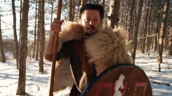 谨慎的中世纪武士冬天手持长矛和盾牌在森林中行走