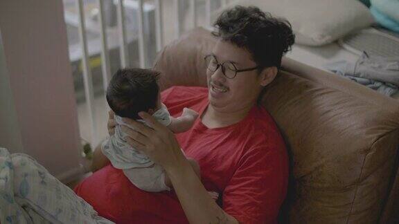 快乐的亚洲父亲抱着婴儿男孩说话和玩