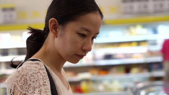 亚洲女孩在超市货架上挑选商品
