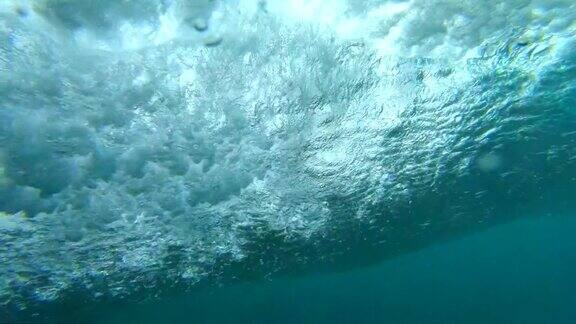 慢镜头水下:大桶状波浪冲向宁静的岩石岛屿