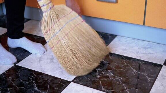 现代厨房里的妇女用旧扫帚和簸箕扫瓷砖地板