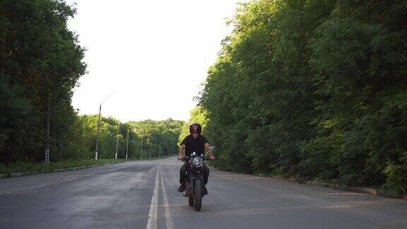 摩托车手在乡村公路上飞驰咖啡车手摩托车冒险生活方式