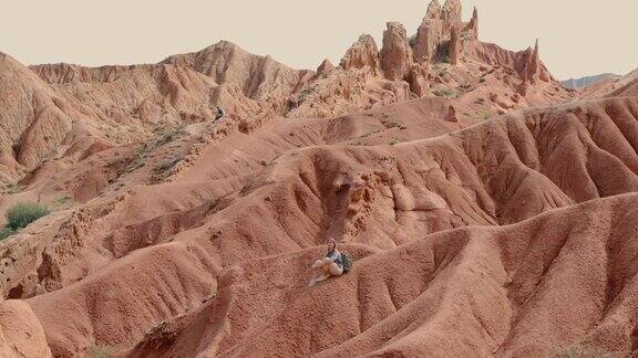 年轻女子背包客在吉尔吉斯斯坦探索彩色纹理的峡谷