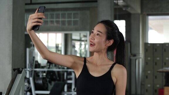 一位美女在健身房里用智能手机自拍