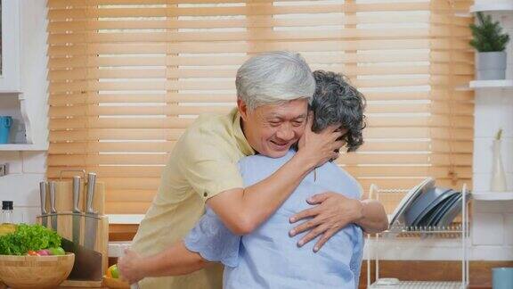 老年亚洲男人在安慰抑郁的老年妇女时站在家里厨房里让退休的人情绪激动