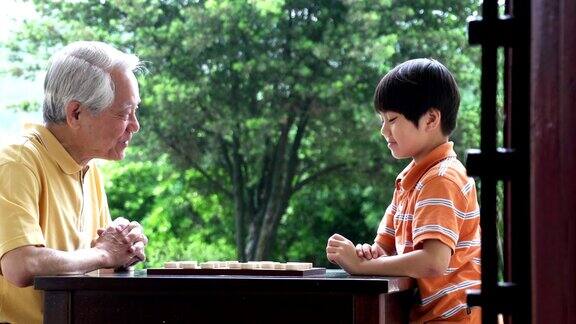 爷爷和孙子在公园里下中国象棋