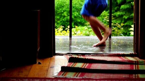 女学生跑出家门在雨中在潮湿的门廊上光着脚跳舞