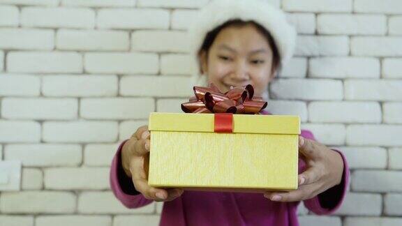 亚洲快乐女孩送礼盒在砖墙背景上