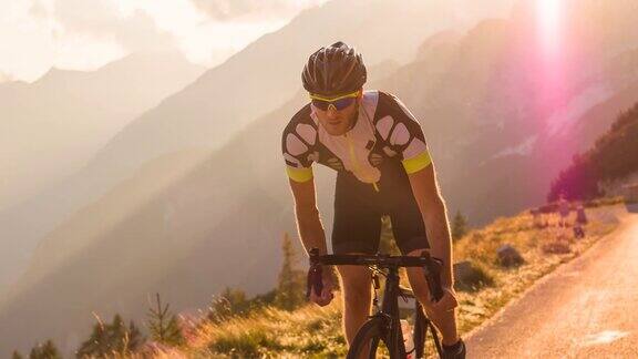 男道骑车人骑着自行车在山路上被阳光照亮