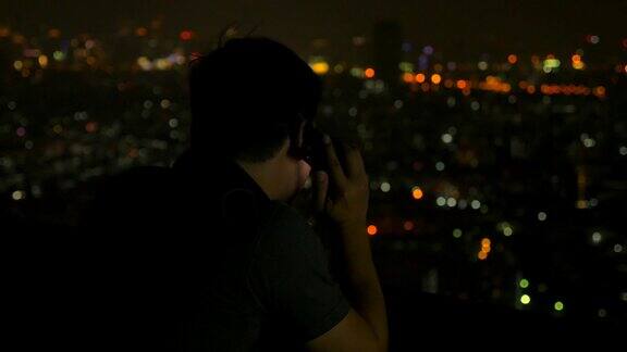 一个亚洲男人晚上在城市里一边打电话一边挂断电话