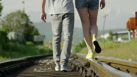 慢镜头特写:一对情侣走在铁轨上