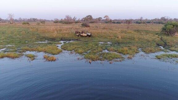 在博茨瓦纳的奥卡万戈三角洲一群河马在河里游泳一辆旅游四驱游猎车在看着它们