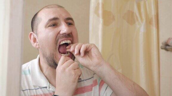 用牙线清洁牙齿男子在镜子前用牙线刷牙