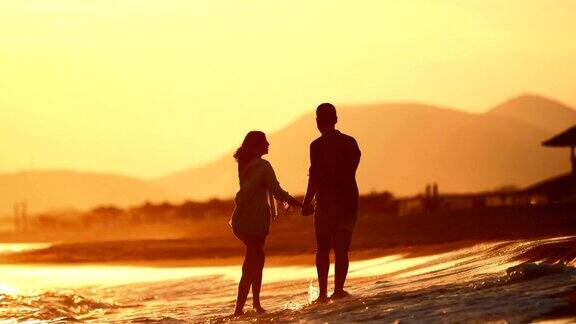 年轻夫妇在海滩上享受浪漫的日落