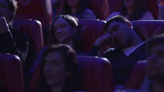 当人们在电影院看电影时男人正在睡觉