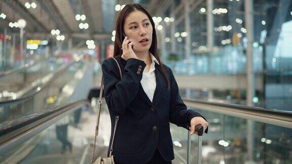 忙碌的女商人一边上机场的自动扶梯一边打电话