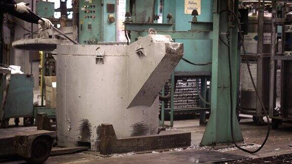 熔炼铝时操作者努力工作将熔化的金属从钢包上攻丝到保温炉压铸机上