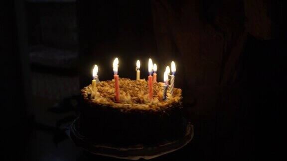 带蜡烛的生日蛋糕抱在怀里的女人黑暗的房间里燃烧着10支蜡烛